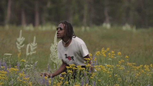 A Man In A Field Of Flowers Wearing A Boy Shirt GIF