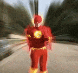 A Man In A Flash Costume Is Running Down A Street . GIF