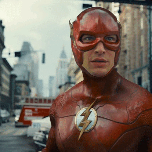 A Man In A Flash Costume Stands In A City Street GIF