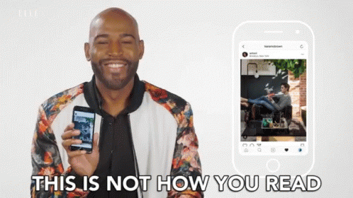 A Man In A Floral Jacket Is Holding A Cell Phone In Front Of A Phone That Says " This Is Not How You Read " GIF