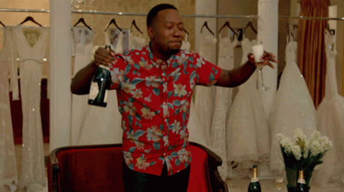 A Man In A Floral Shirt Holds A Bottle Of Champagne And A Glass GIF