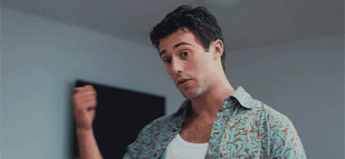 a man in a floral shirt is holding his fist up