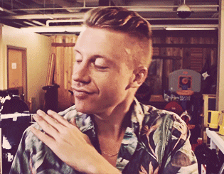 A Man In A Floral Shirt Is Smiling With His Hands On His Shoulder GIF