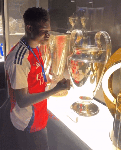 A Man In A Fly Emirates Shirt Holds A Large Trophy GIF