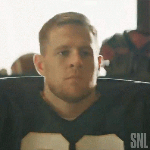 A Man In A Football Uniform Is Sitting In A Chair Looking At The Camera . GIF