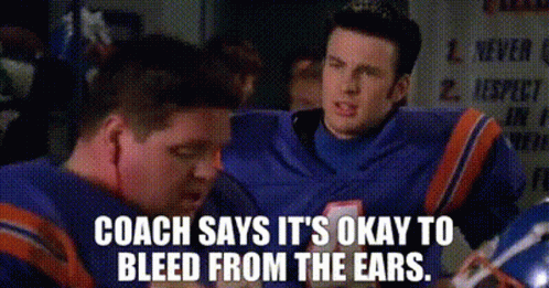 A Man In A Football Uniform Is Talking To Another Man In A Locker Room . GIF