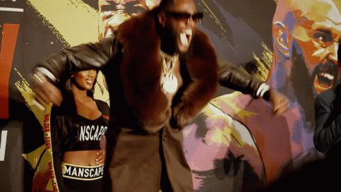 A Man In A Fur Coat Is Standing Next To A Woman Wearing A Manscape Crop Top GIF