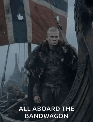 A Man In A Fur Coat Is Standing On A Boat With The Words " All Aboard The Bandwagon " Below Him GIF