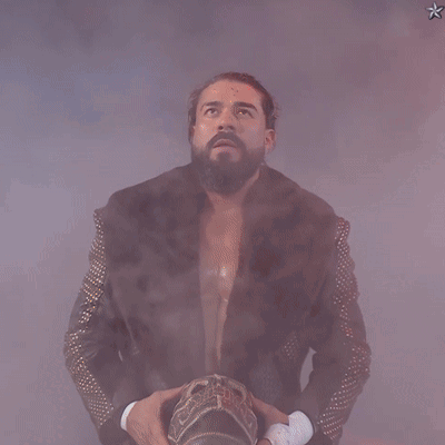A Man In A Fur Coat With Studded Sleeves Is Holding A Crown GIF