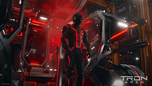 Man In Futuristic Suit In Front Of Tron Sign GIF