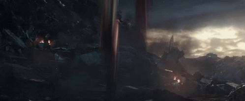 A Man In A Futuristic Suit With Wings Is Standing In The Dark GIF