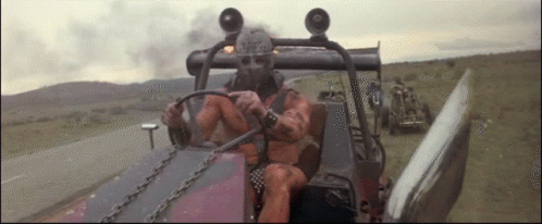 A Man In A Gas Mask Is Driving A Vehicle GIF