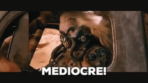 A Man In A Gas Mask Is Sitting In A Car With The Words Mediocre Written On The Bottom . GIF