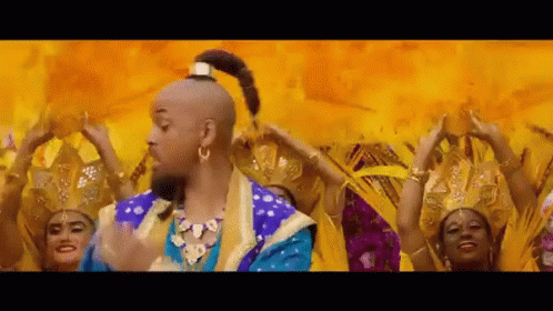 A Man In A Genie Costume Is Dancing In Front Of A Group Of Women . GIF