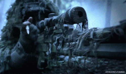 A Man In A Ghillie Suit Holding A Sniper Rifle With Attacktics.tumblr Written On The Bottom GIF