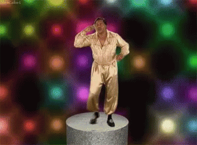 a man in a gold jumpsuit is standing on a podium in front of a colorful background .