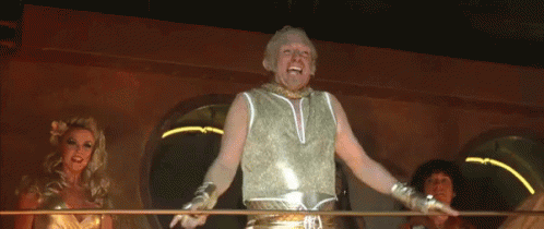A Man In A Gold Tank Top Is Standing In Front Of Two Women GIF