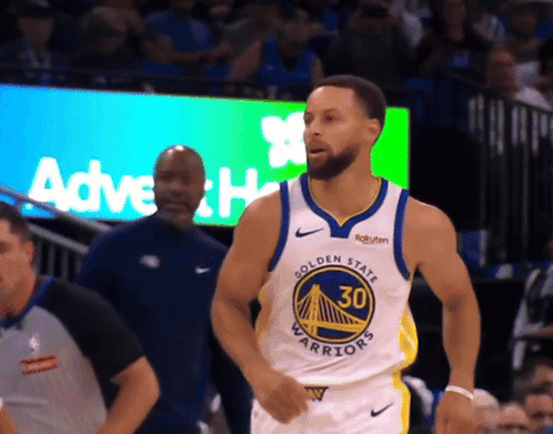 a man in a golden state warriors jersey stands in front of a crowd