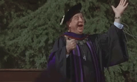 A Man In A Graduation Cap And Gown Is Giving A Speech With His Arms Outstretched . GIF