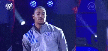 A Man In A Gray Jacket Is Standing On A Stage In Front Of A Blue Background . GIF