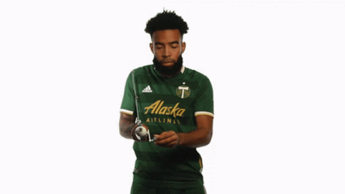 A Man In A Green Alaska Airlines Jersey Holds A Stick GIF