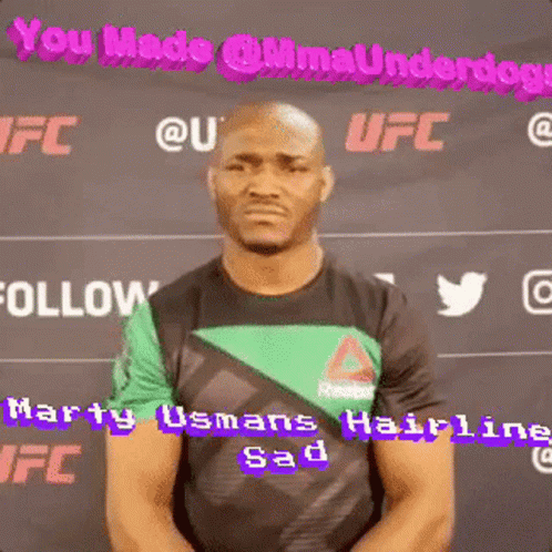 A Man In A Green And Black Shirt Is Standing In Front Of A Sign That Says Ufc GIF