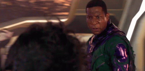 A Man In A Green And Purple Jacket Is Standing Next To Another Man In A Purple Jacket . GIF