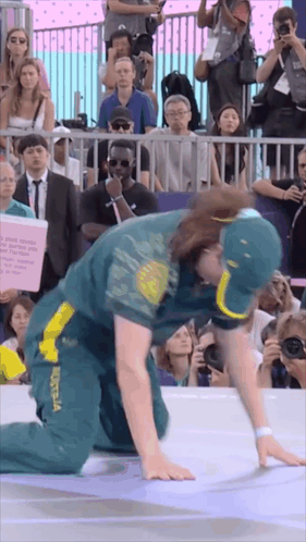A Man In A Green And Yellow Outfit With Australia On It Is Kneeling Down In Front Of A Crowd GIF