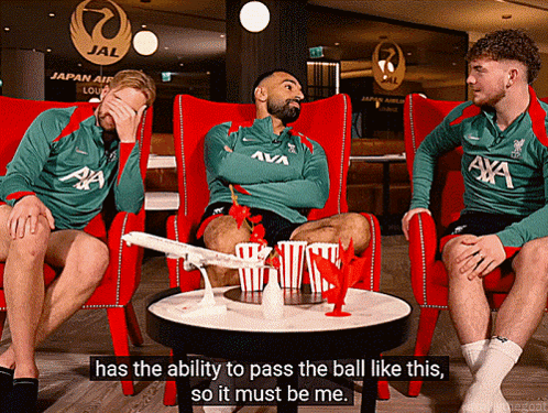 A Man In A Green Axa Shirt Sits In A Red Chair GIF