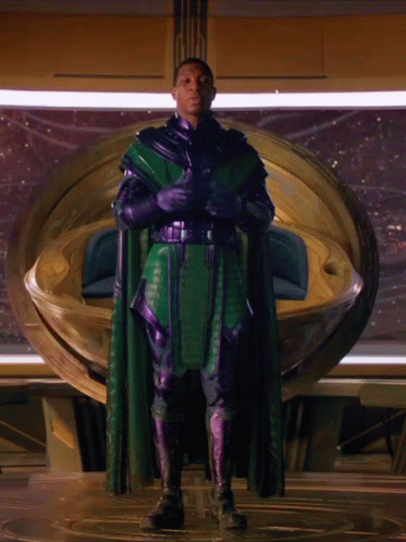 A Man In A Green Cape And Purple Gloves GIF