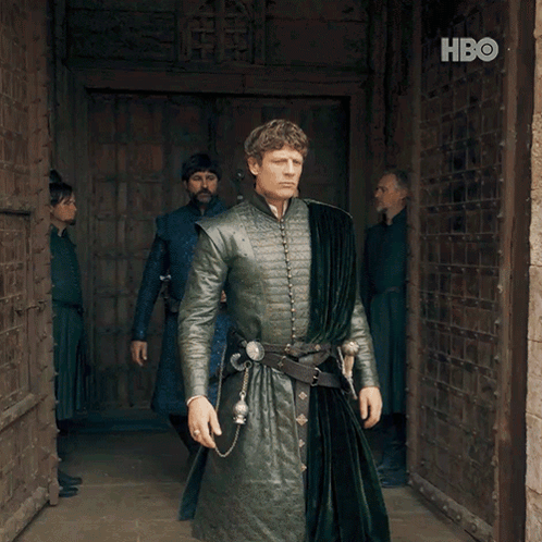 A Man In A Green Coat Stands In Front Of A Door With Hbo Written On It GIF