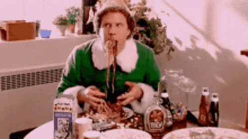 A Man In A Green Dress Is Eating Spaghetti At A Table . GIF