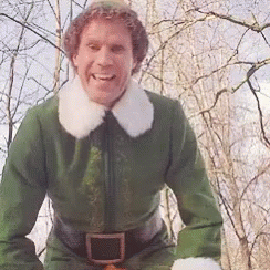 A Man In A Green Elf Costume Is Smiling And Looking At The Camera GIF
