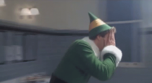 A Man In A Green Elf Costume Is Standing In A Bathroom Next To A Sign That Reads Monday GIF