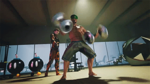 A Man In A Green Hat Holds A Pair Of Dumbbells In A Gym GIF