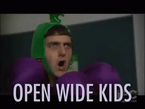 A Man In A Green Hat Is Holding Purple Pom Poms And The Words `` Open Wide Kids '' Are Behind Him . GIF