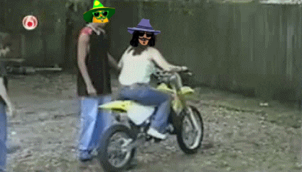 A Man In A Green Hat Is Standing Next To A Woman On A Motorcycle GIF