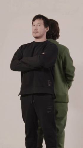 A Man In A Green Hoodie And A Man In A Black Hoodie Are Standing Back To Back GIF