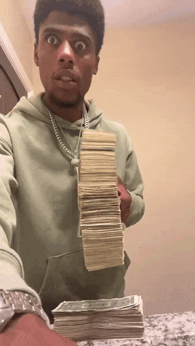 A Man In A Green Hoodie Holds Up A Stack Of Money GIF