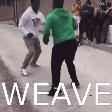 A Man In A Green Hoodie Is Dancing With Another Man In A White Hoodie On A Street . GIF