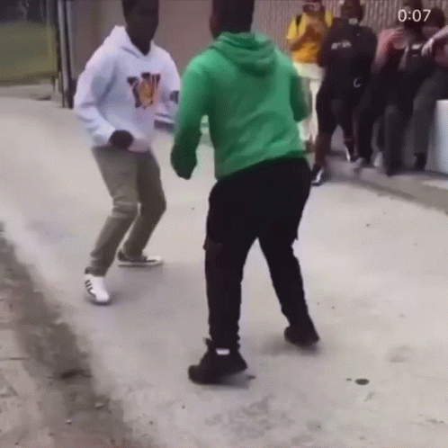A Man In A Green Hoodie Is Dancing With Another Man GIF