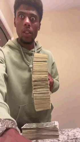 A Man In A Green Hoodie Is Holding A Stack Of Money .. GIF