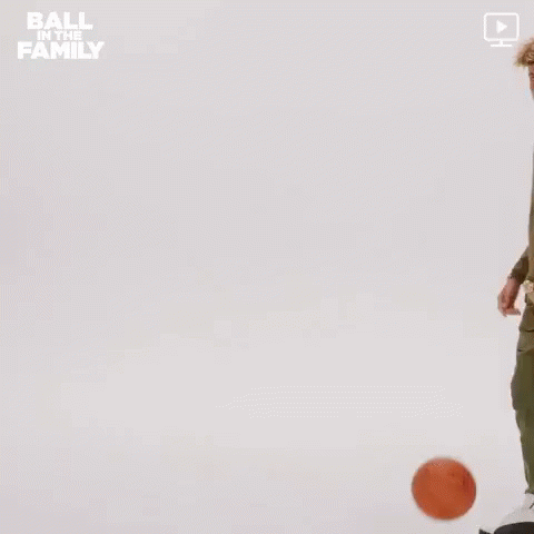 a man in a green jacket is holding a basketball in his hand .