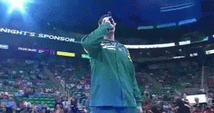 A Man In A Green Jacket Is Singing Into A Microphone In Front Of A Banner That Says Tonight 'S Sponsor GIF