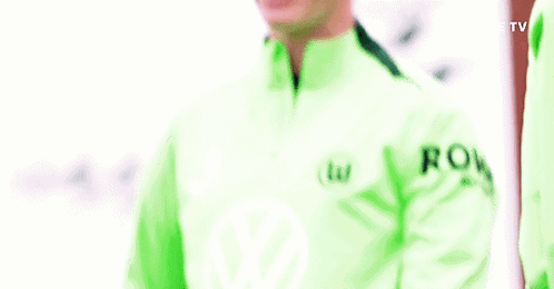 A Man In A Green Jacket Is Smiling And Holding His Arms Up . GIF