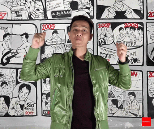 Man In Green Jacket In Front Of Comic Wall GIF