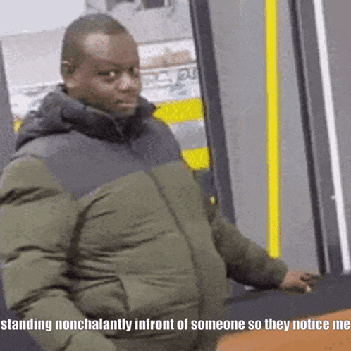A Man In A Green Jacket Is Standing Nonchalantly In Front Of Someone So They Notice Me GIF