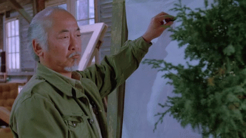 A Man In A Green Jacket Writes On A White Board GIF