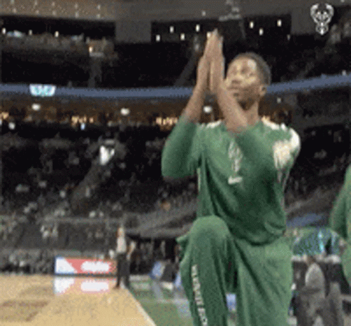 A Man In A Green Jersey Is Kneeling Down And Clapping GIF
