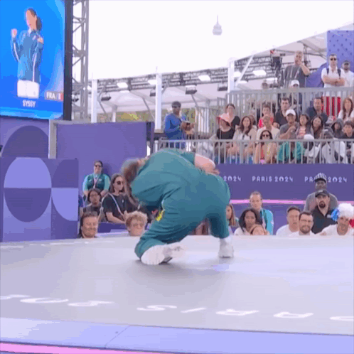 A Man In A Green Jumpsuit Is Doing A Trick In Front Of A Crowd At The Paris 2024 Olympics GIF